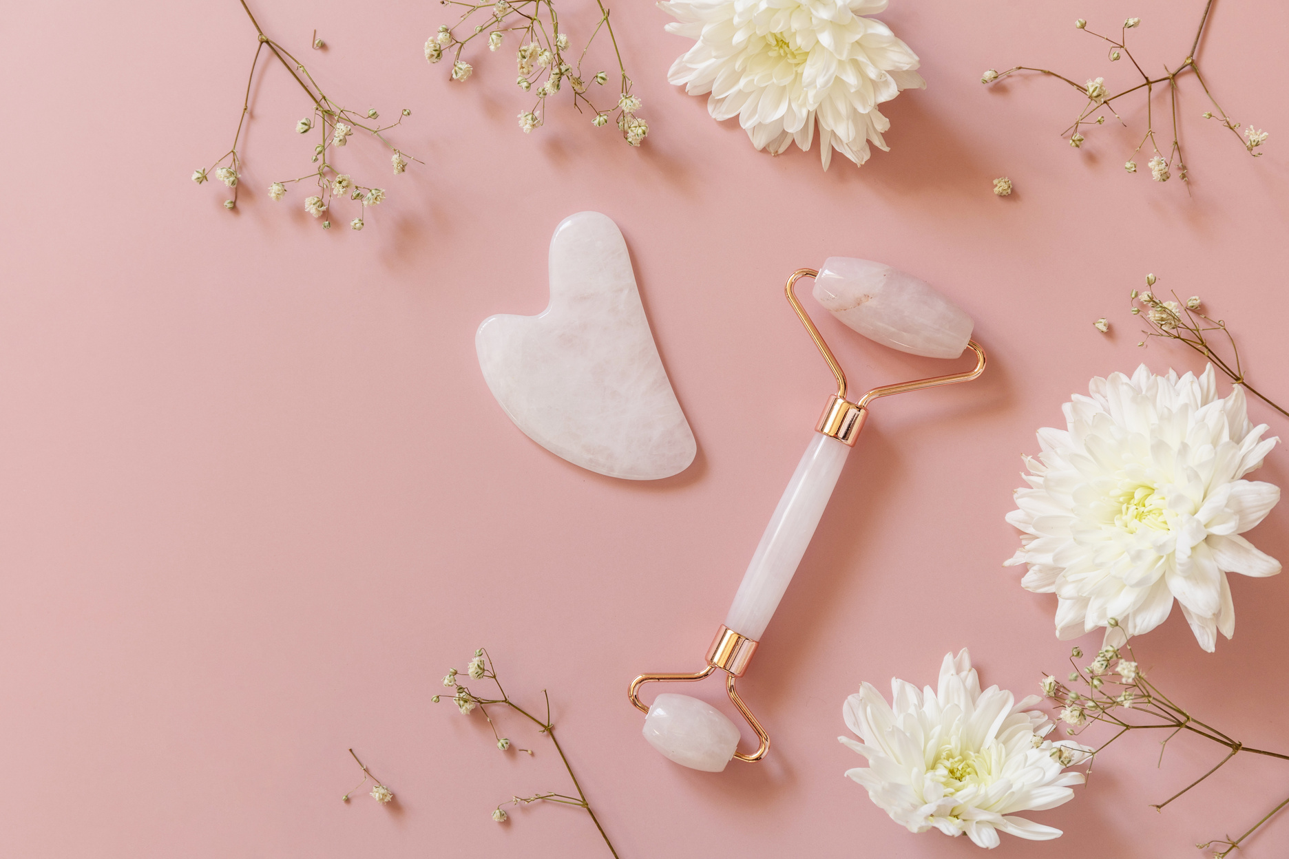 Rose Quartz Facial Massage Roller over Pink Background with Gyps